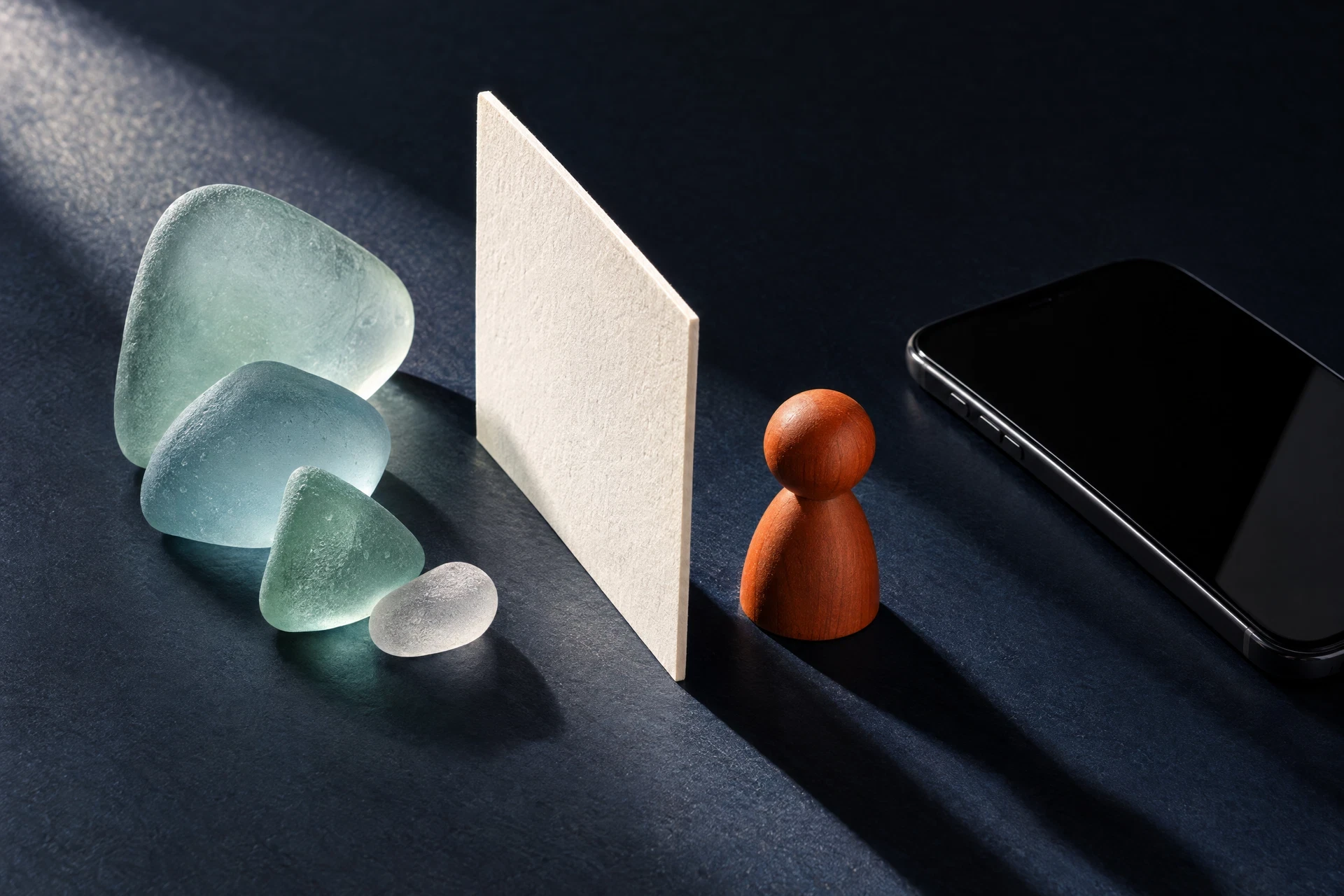 Sea glass shapes, chalk card and generic phone on midnight surface